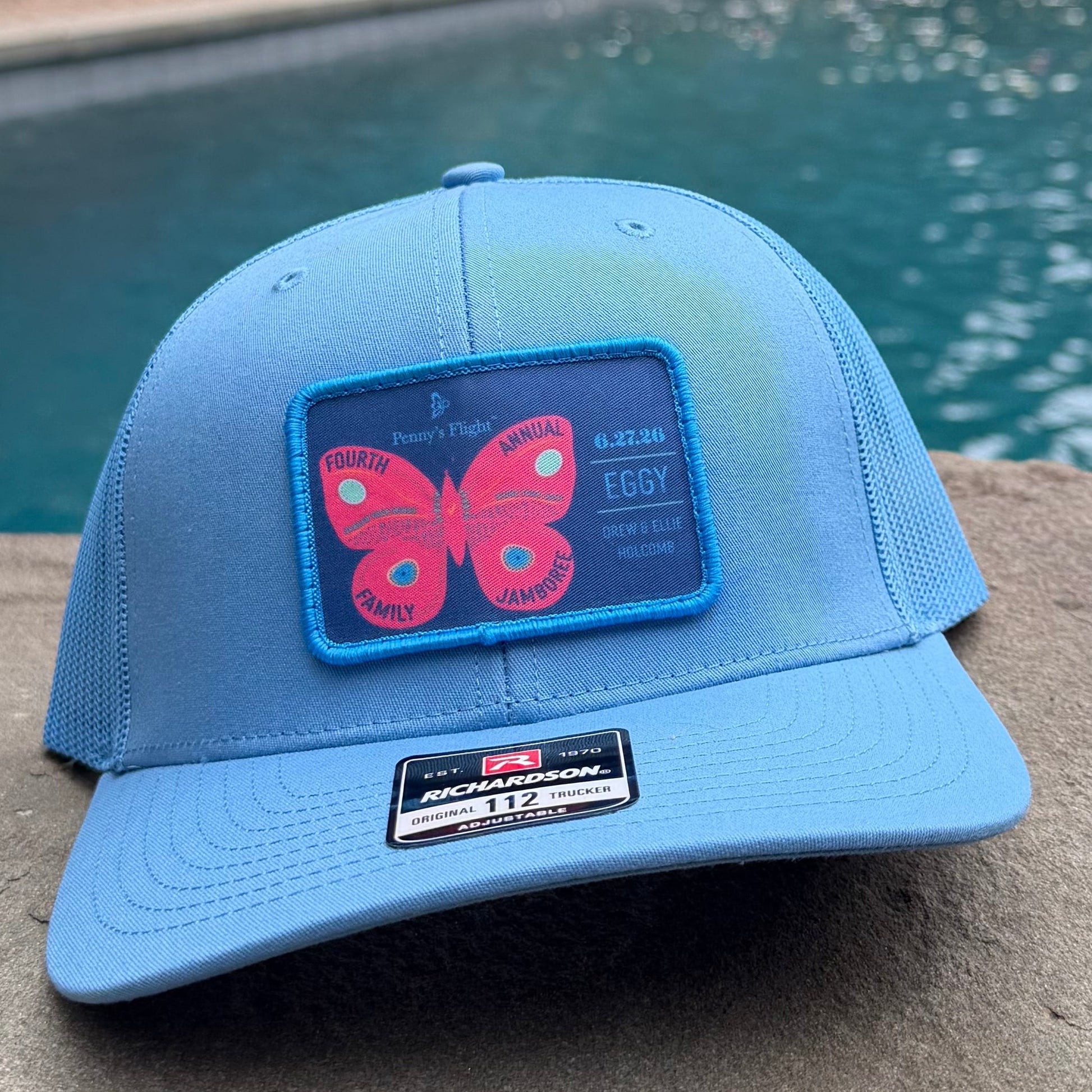 Blue hat on a stone ledge by a body of water.